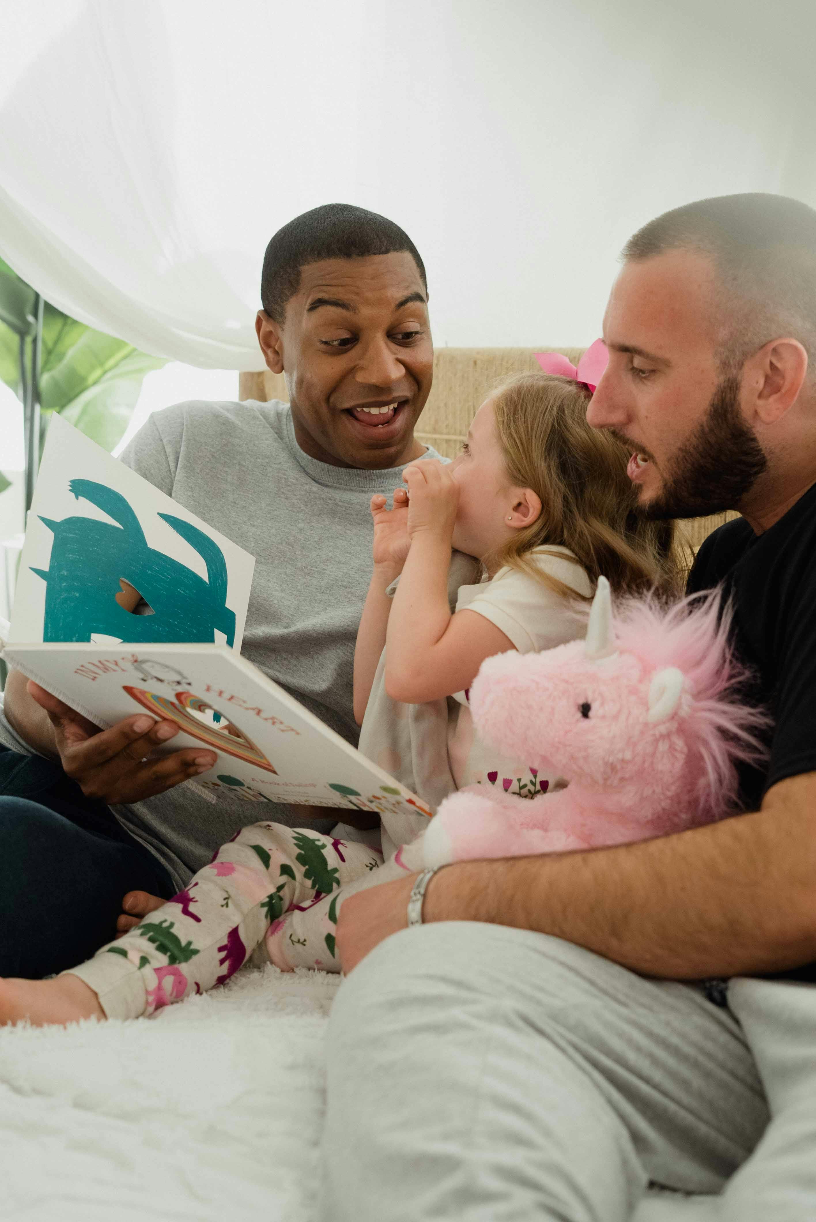 photograph of a girl reading a book with her parents