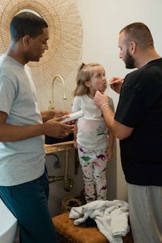 Two fathers helping their daughter brush her teeth in a cozy bathroom setting, showcasing family bonding.