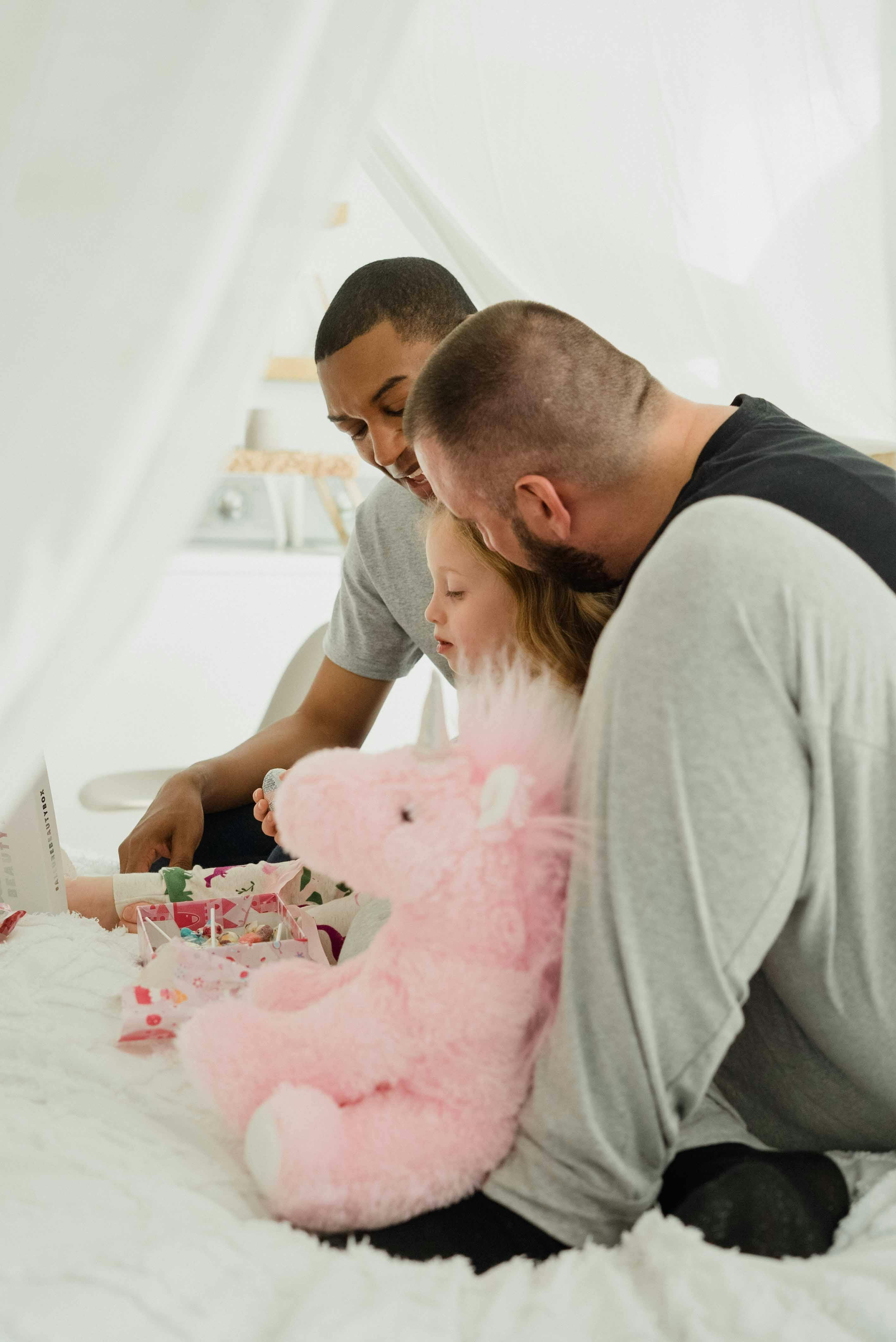 photo of a girl playing with her parents on the bed