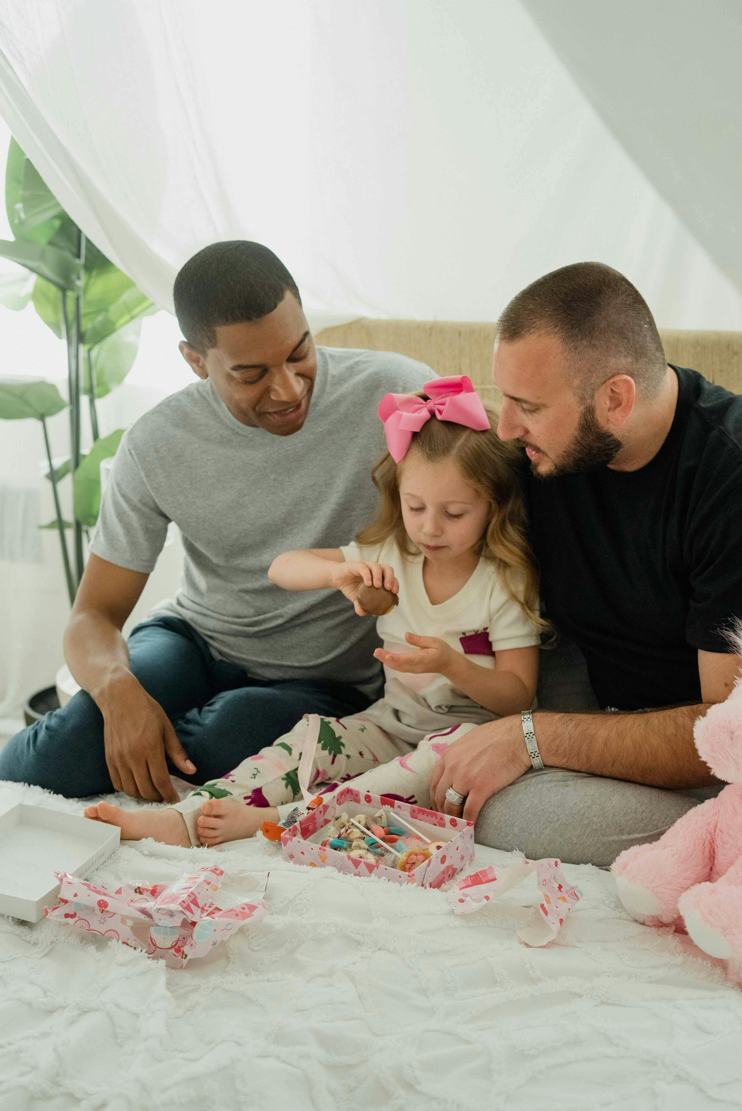 men and a young girl sitting together on a bed