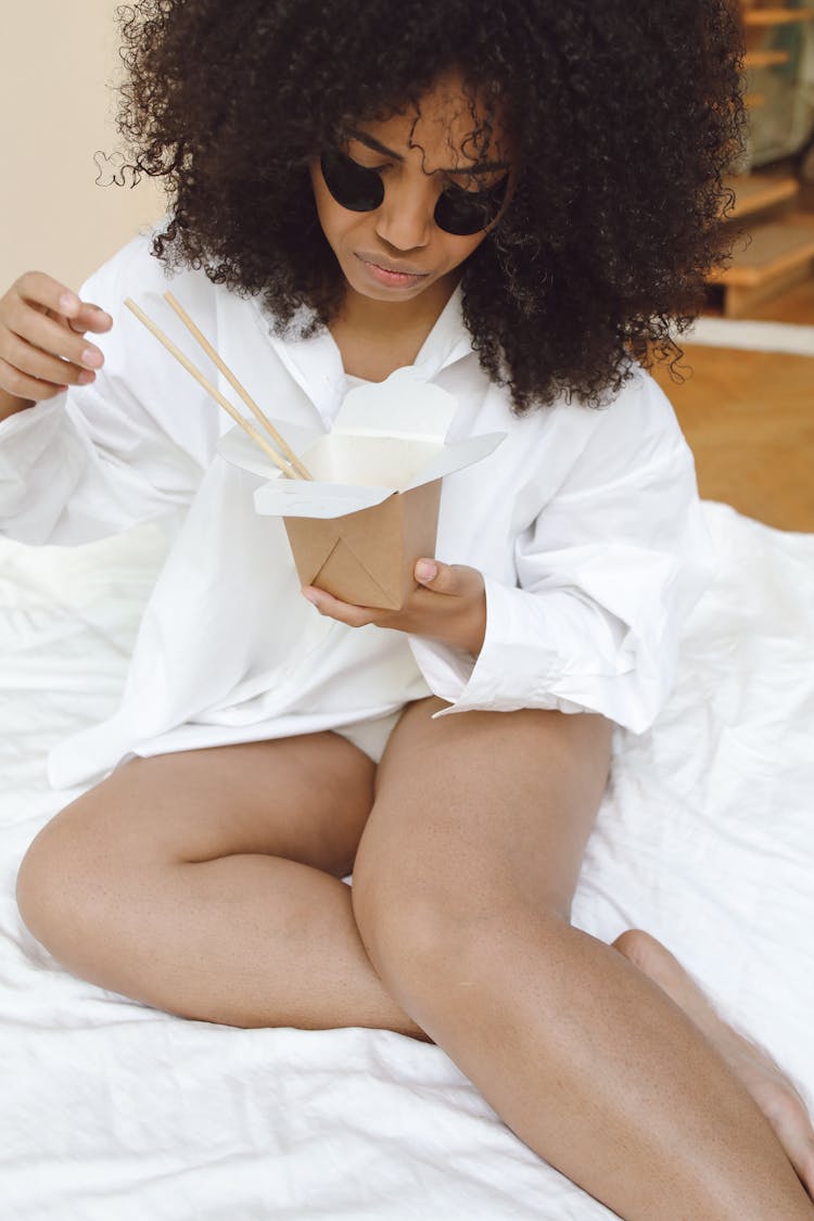 Photo Of A Woman With Under Eye Patches Eating From A Takeout Box