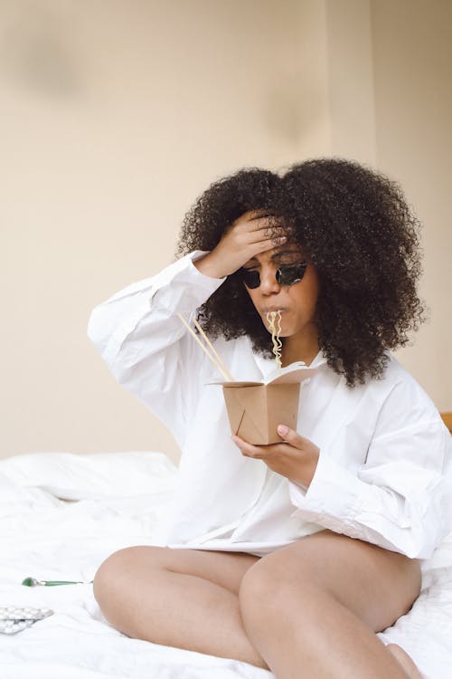 Photo of a Woman with a Headache Eating Noodles