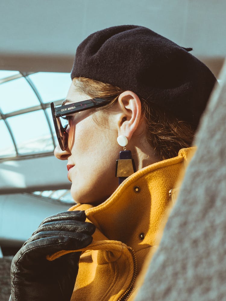 Woman In Yellow Trench Coat, Black Leather Gloves, Black Sunglasses And Black Hat