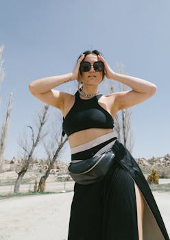 Stylish woman posing outdoors in Turkey, showcasing chic fashion accessories under a clear blue sky.