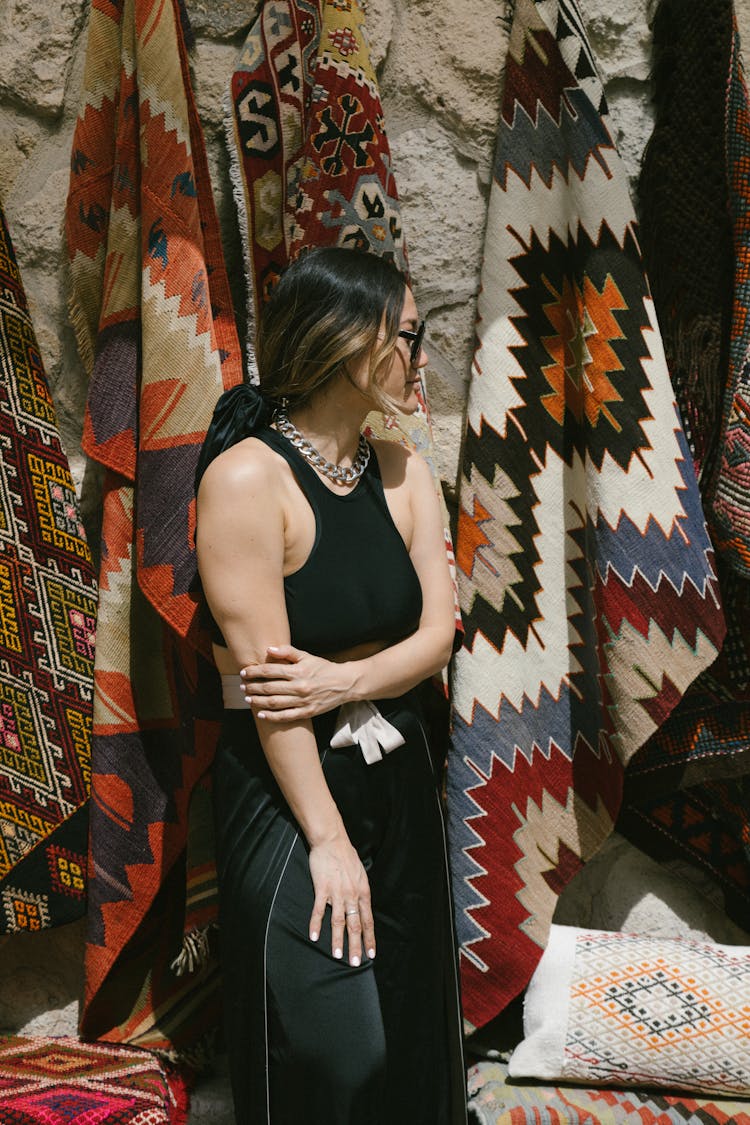 Woman In Black Top And Black Pants Standing Beside Patterned Rugs