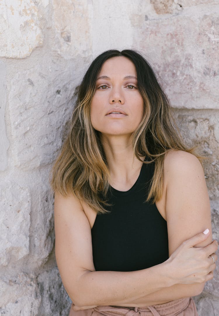 A Woman In Black Tank Top Leaning On Granite Wall