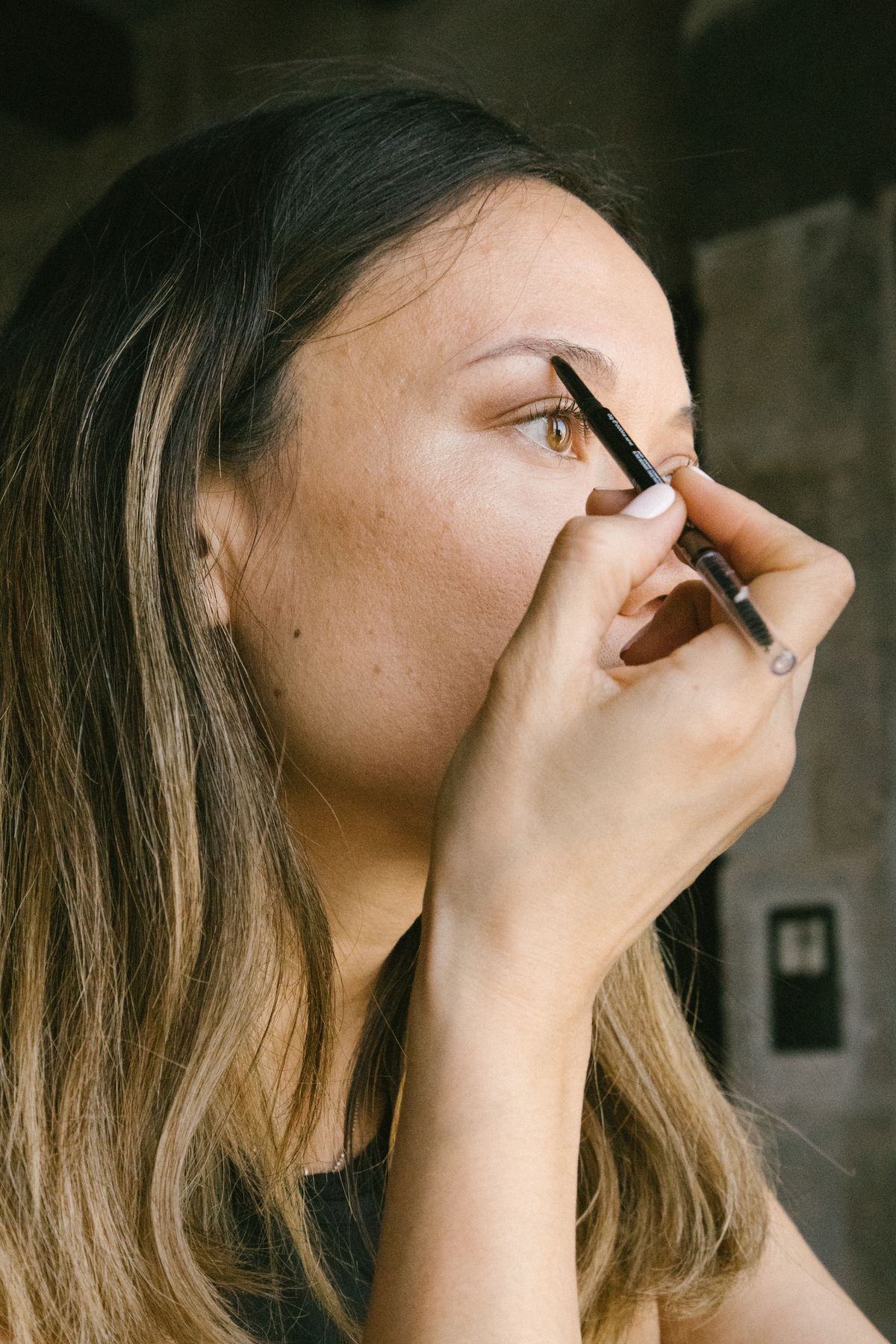 Close-up of a woman applying eyebrow makeup with a fine brow pencil
