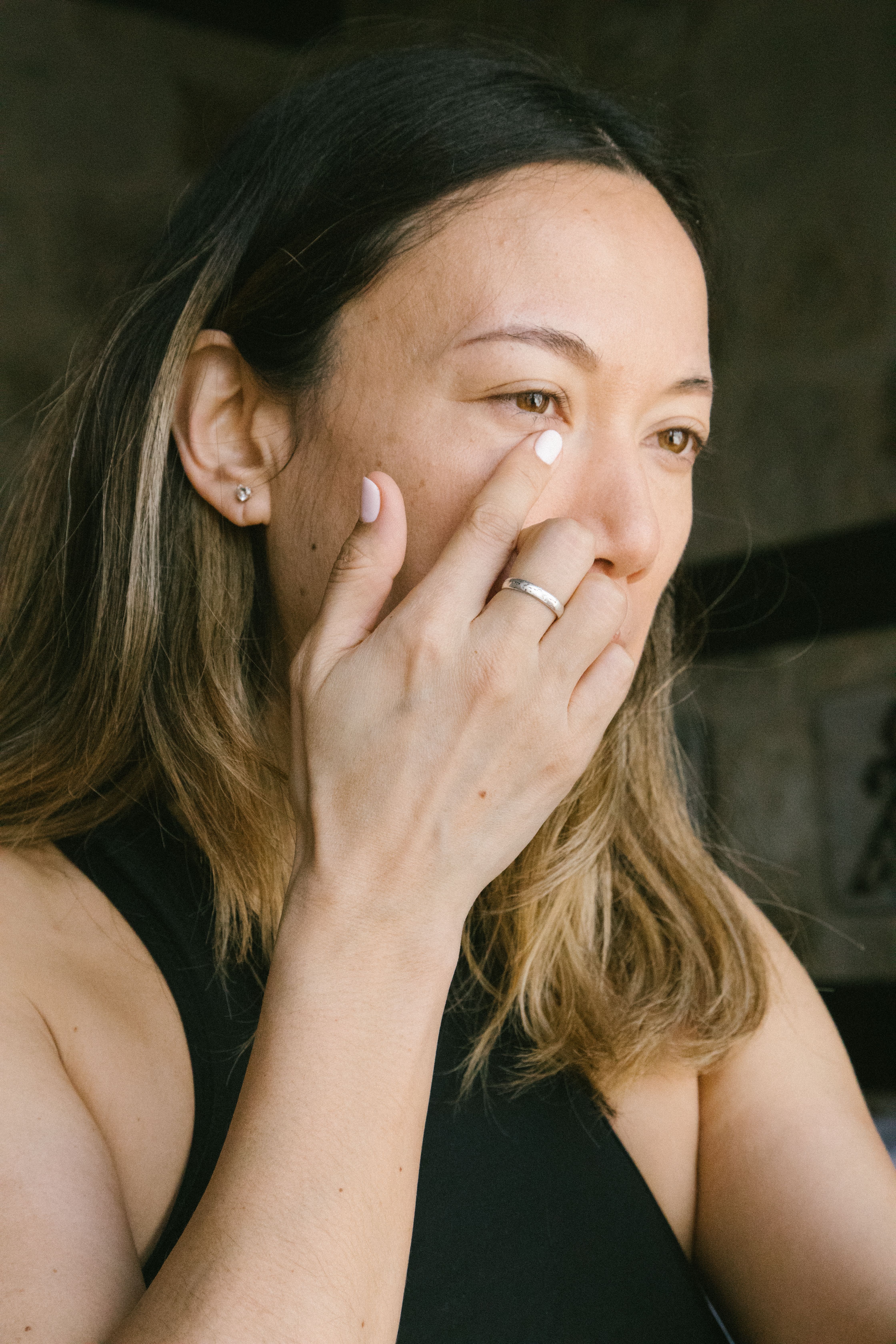 Close-up of a woman thinking with her hand on face, showcasing a wedding ring.