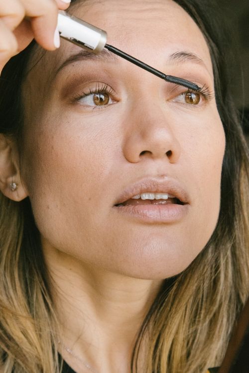 Free Close-up portrait of a woman applying mascara, highlighting her beauty routine. Stock Photo