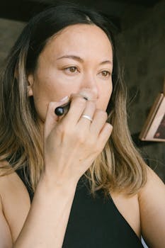Close-up of a woman applying makeup with a brush indoors, showcasing a beauty routine.