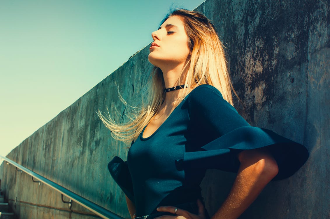 Free Woman Wearing Blue Scoop-neck Top Standing Near Gray Concrete Wall Stock Photo