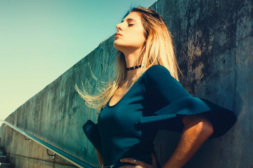 Mujer Vistiendo Azul Escote Redondo De Pie Junto A La Pared De Hormigón Gris