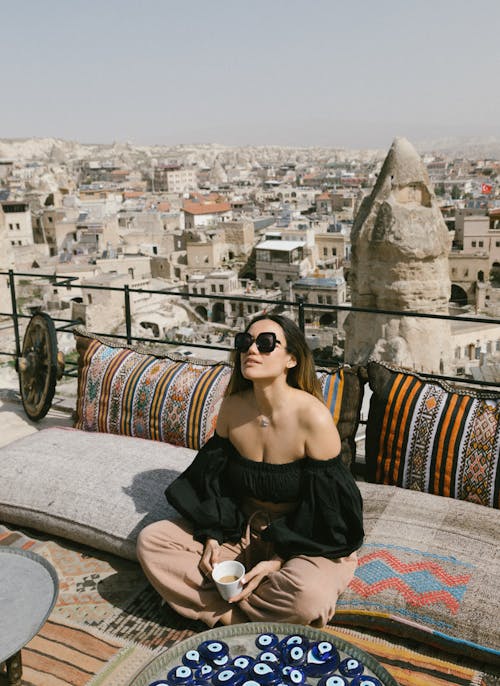 Attractive Woman in Sexy Blouse Sitting Cross Legged on Roof Terrace 