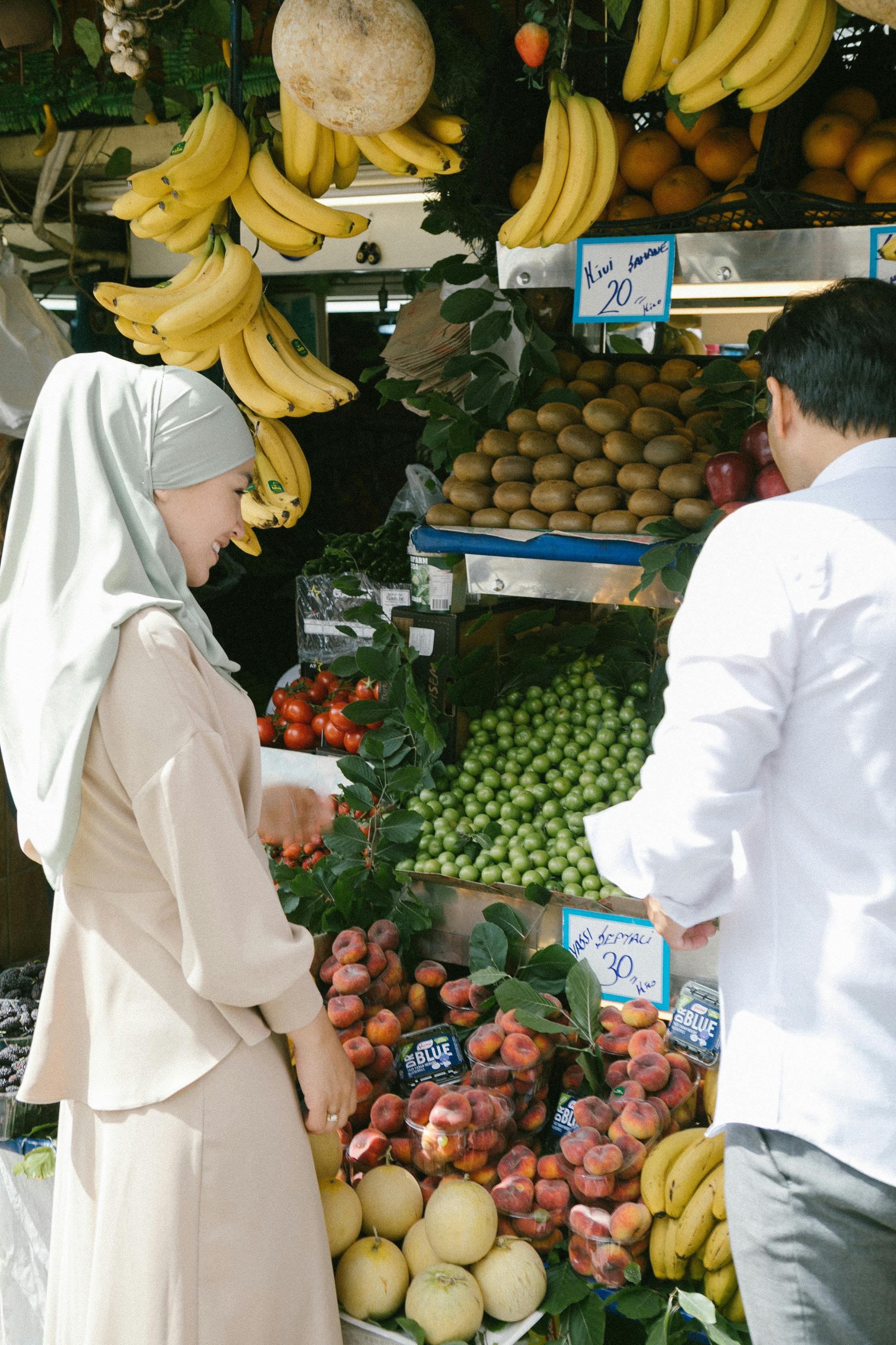 A woman in hijab and a man shop for fresh fruits at an outdoor market in Istanbul.