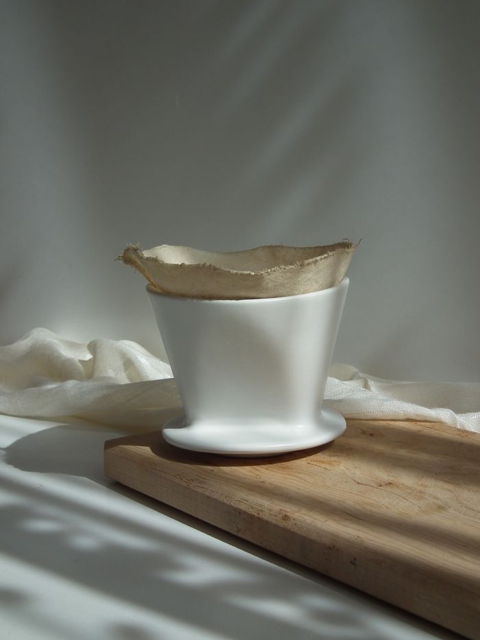 Ceramic coffee dripper with filter on a wooden board — photo by ly on Pexels