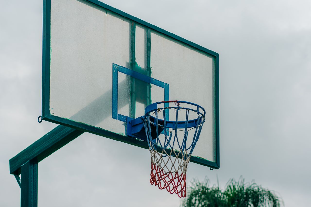 close up of a basketball hoop outdoors with net and backboard against