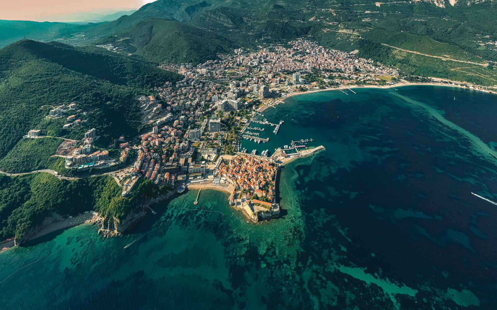 The luxury travel edit of Montenegro — aerial view of a coastal city near green mountains beside the Adriatic Sea on the Bay of Kotor