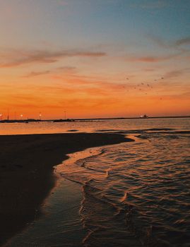 Vivid sunset over the ocean with gentle waves and a scenic view, perfect for tranquil moments.