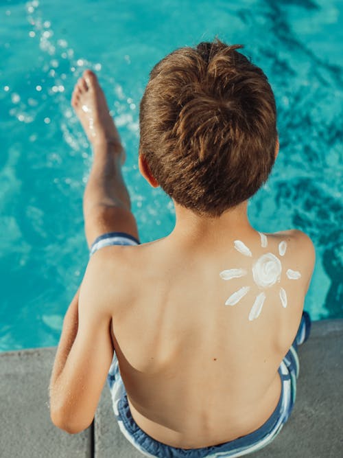 Shirtless Boy Sitting by the Poolside