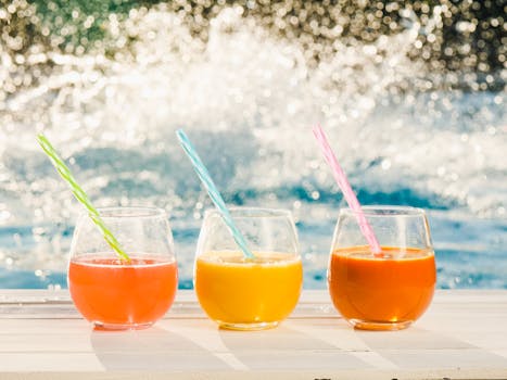 Refreshing colorful fruit juices in glasses by the pool on a sunny day.