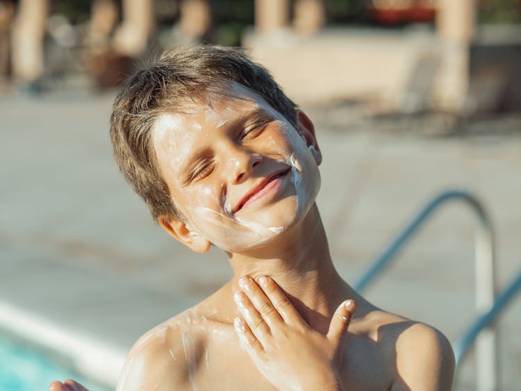 Boy Applying Sunscreen Lotion On His Neck