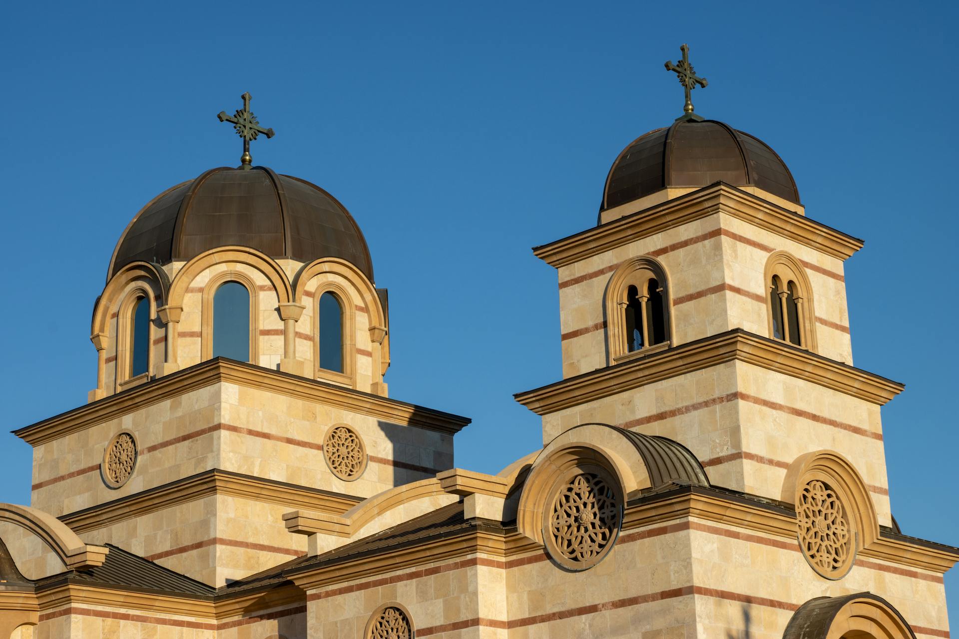 Exterior view of a Serbian Orthodox church under a clear blue sky.