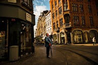 一名男子站在一条充满活力的城市街道上，四周环绕着历史建筑和商店