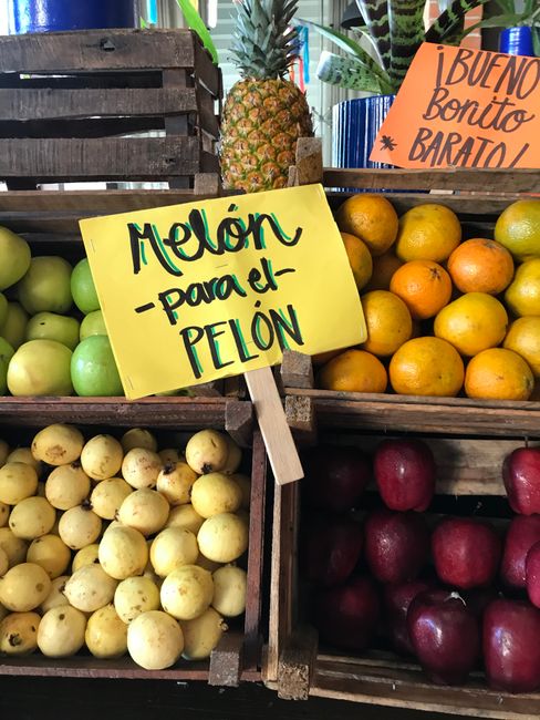 Vibrant fruit stand with melons, citrus, and pineapples at a Mexican market.