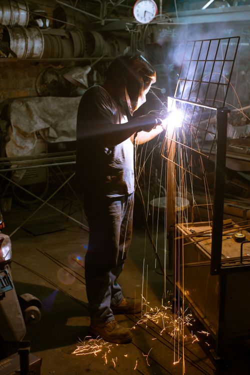 Free Skilled welder working in a workshop, producing bright sparks during metal welding. Stock Photo