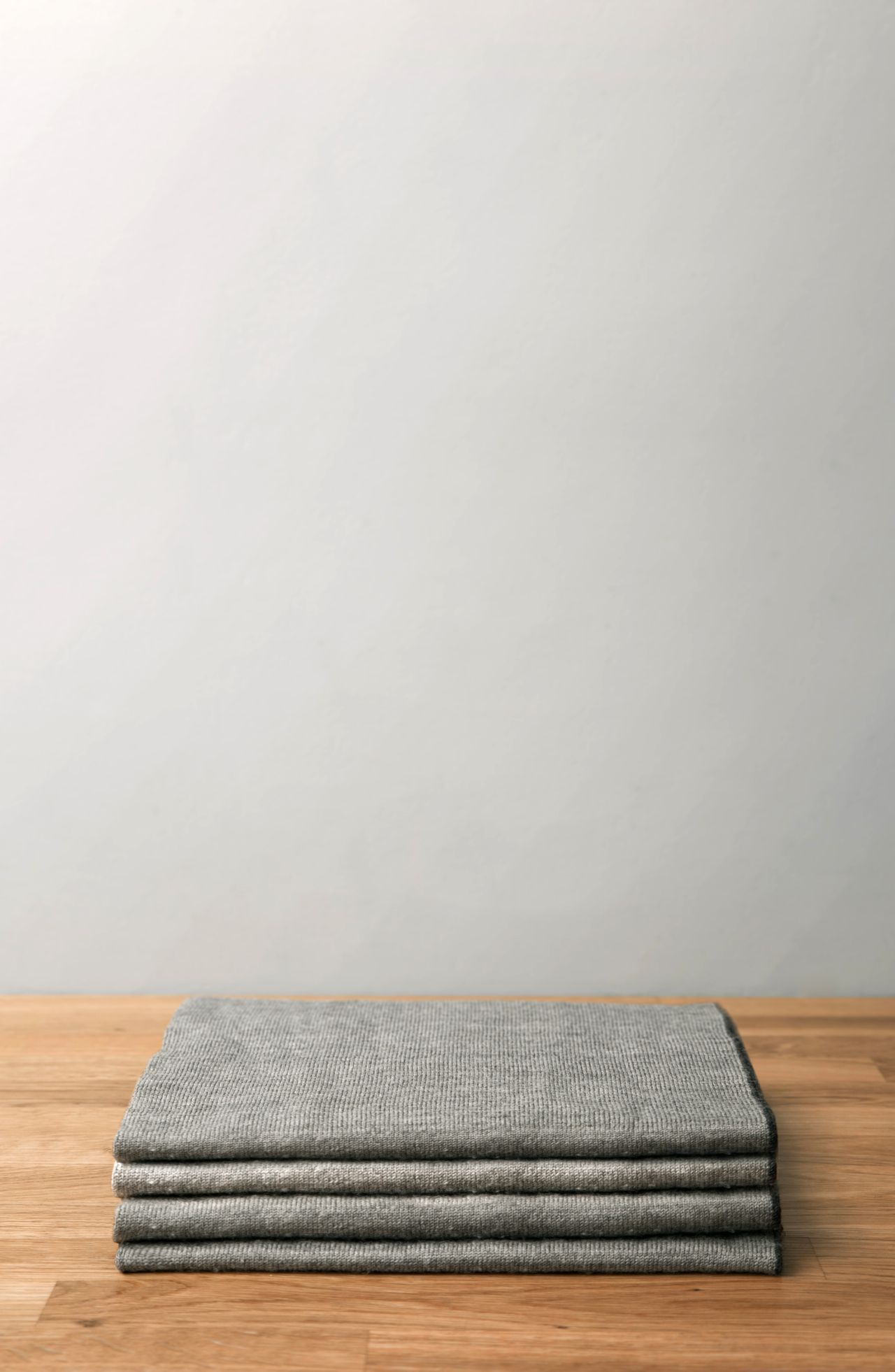 Neatly folded grey wool blanket on a wooden table