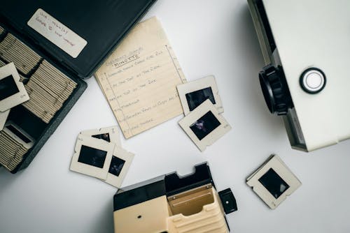 White and Black Projector on White Surface Beside Case