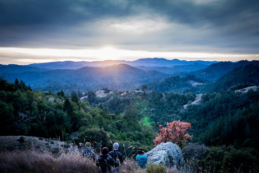 一群徒步旅行者在郁郁葱葱的绿色山脉上，观赏着壮观的天空下的日出