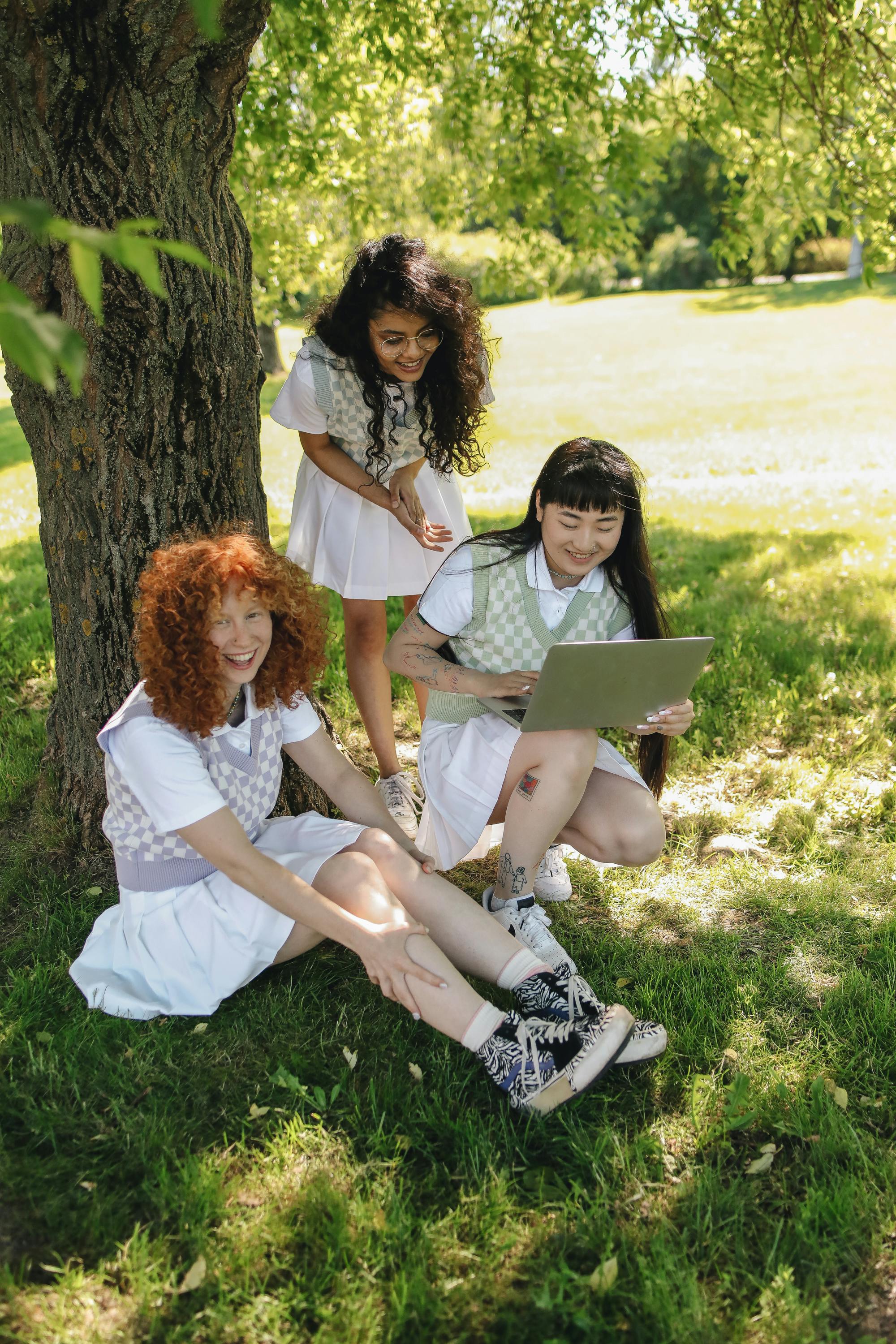 teenage girls wearing uniforms having fun under a tree