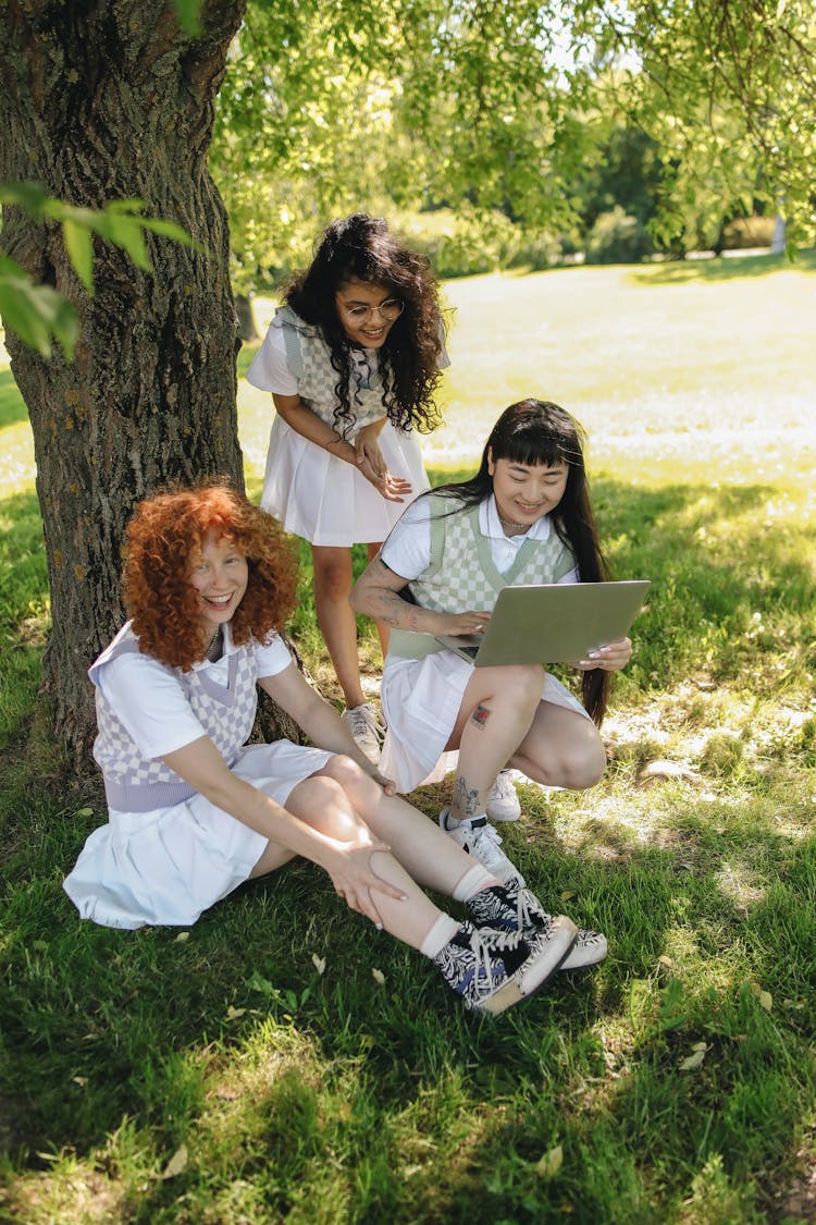 Teenage Girls Wearing Uniforms Having Fun Under A Tree