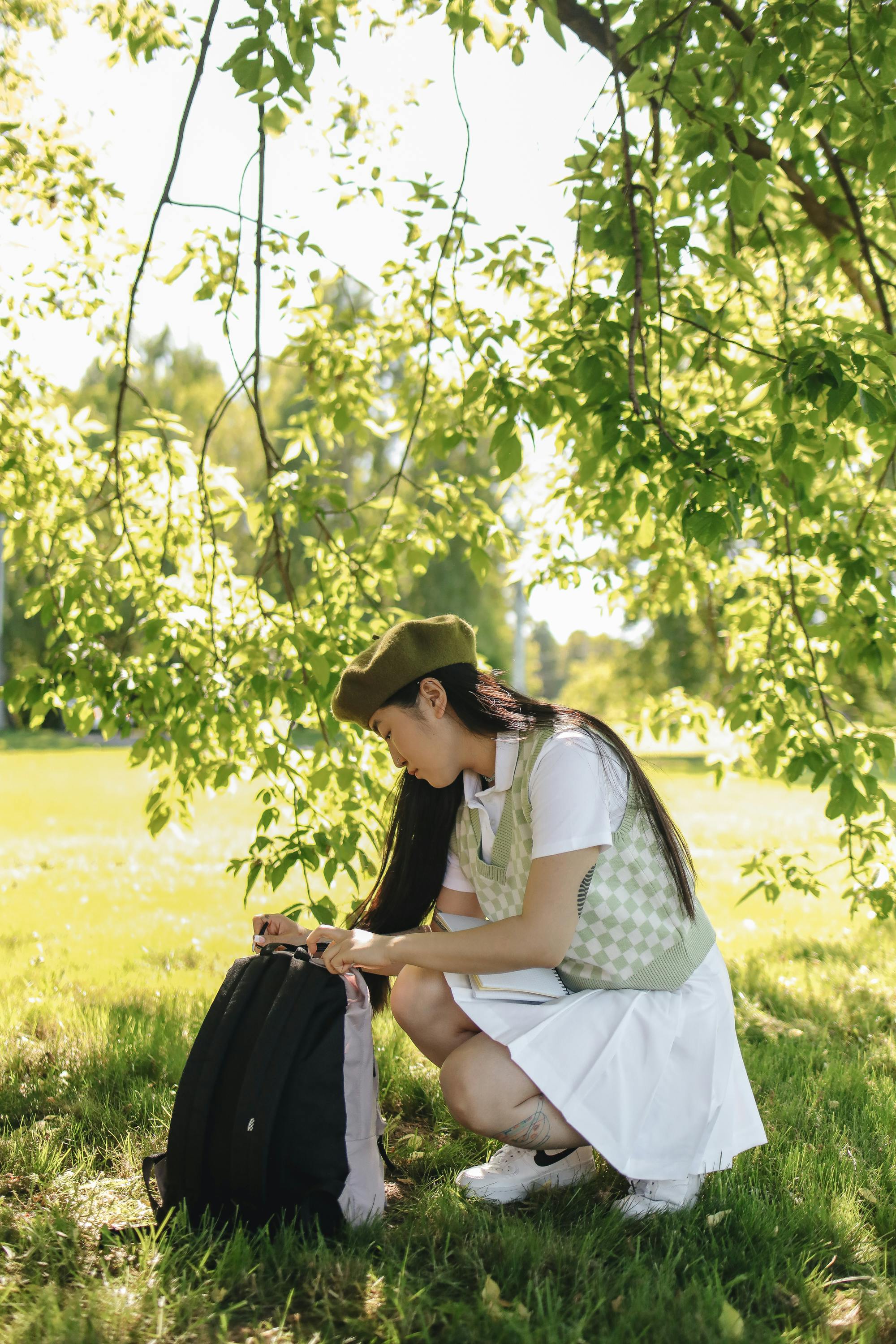 a young woman opening her backpack at a park