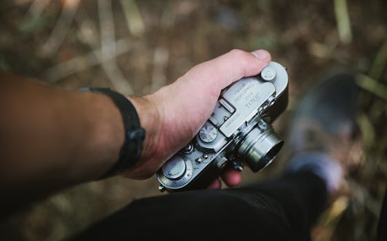 A person holds a vintage camera outdoors, showcasing classic photography equipment.