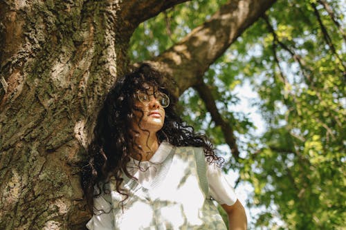 A Young Woman Posing while Leaning on a Tree