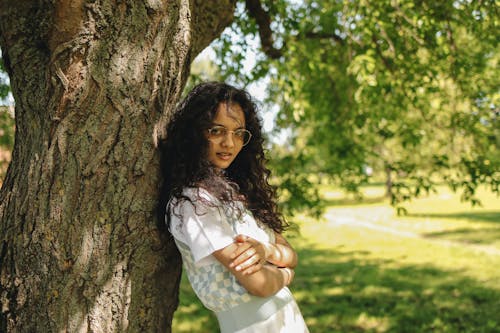 A Young Woman Posing while Leaning on a Tree