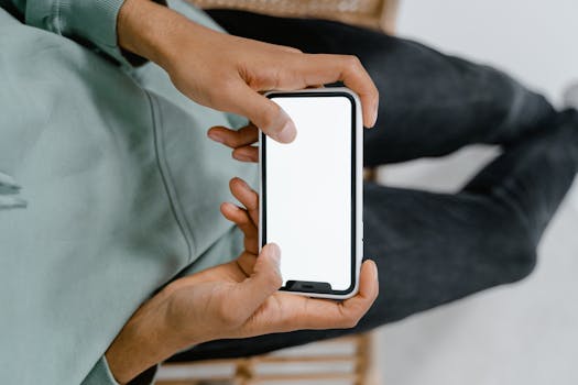 A close-up view of hands holding a smartphone with a blank screen, ideal for digital display mockups.