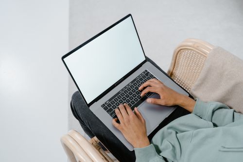 Free Overhead view of a person typing on a laptop in a comfortable armchair indoors. Stock Photo