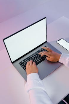 Hands typing on laptop with smartphone on table. Perfect for tech and productivity themes.