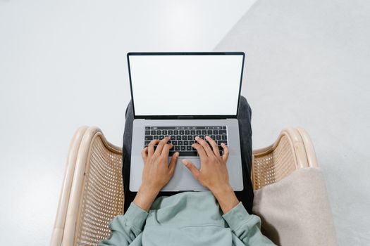 Person typing on a laptop with a blank screen, viewed from above in a modern setting.