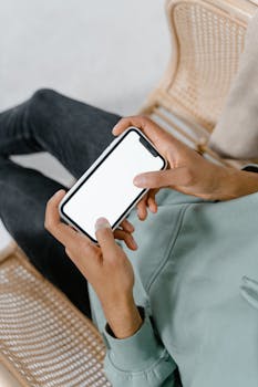 Close-up of hands holding a smartphone with a blank screen, ideal for mockups.