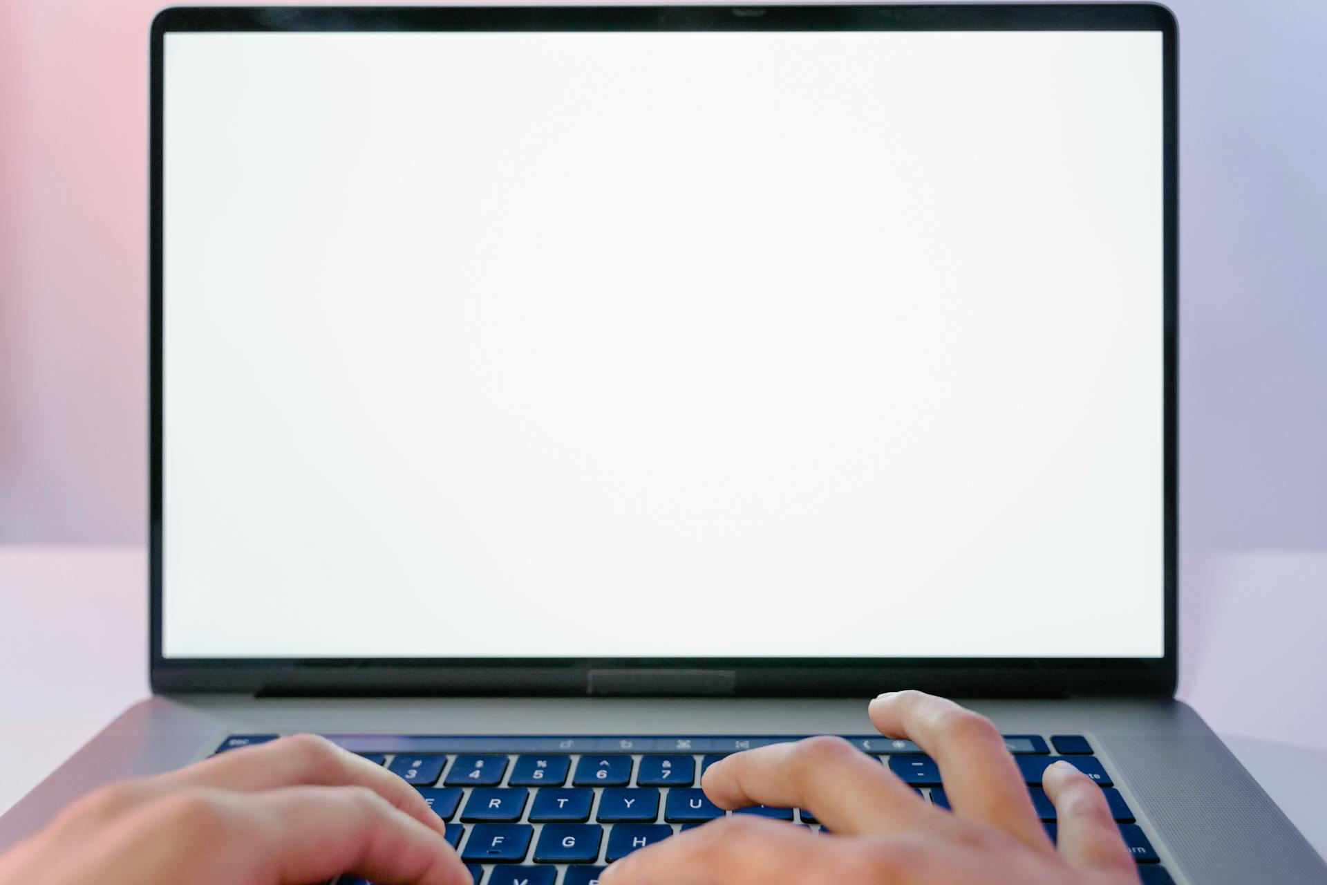 Close-up view of hands typing on a laptop with a blank screen, ideal for design mockups.