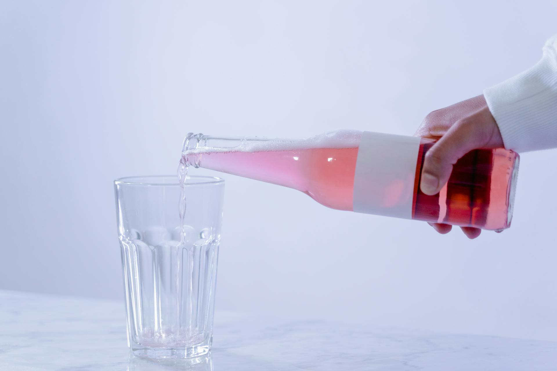 Person Holding a Clear Glass Bottle