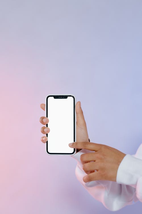 Person Holding White Mobile Phone and Touching the Screen