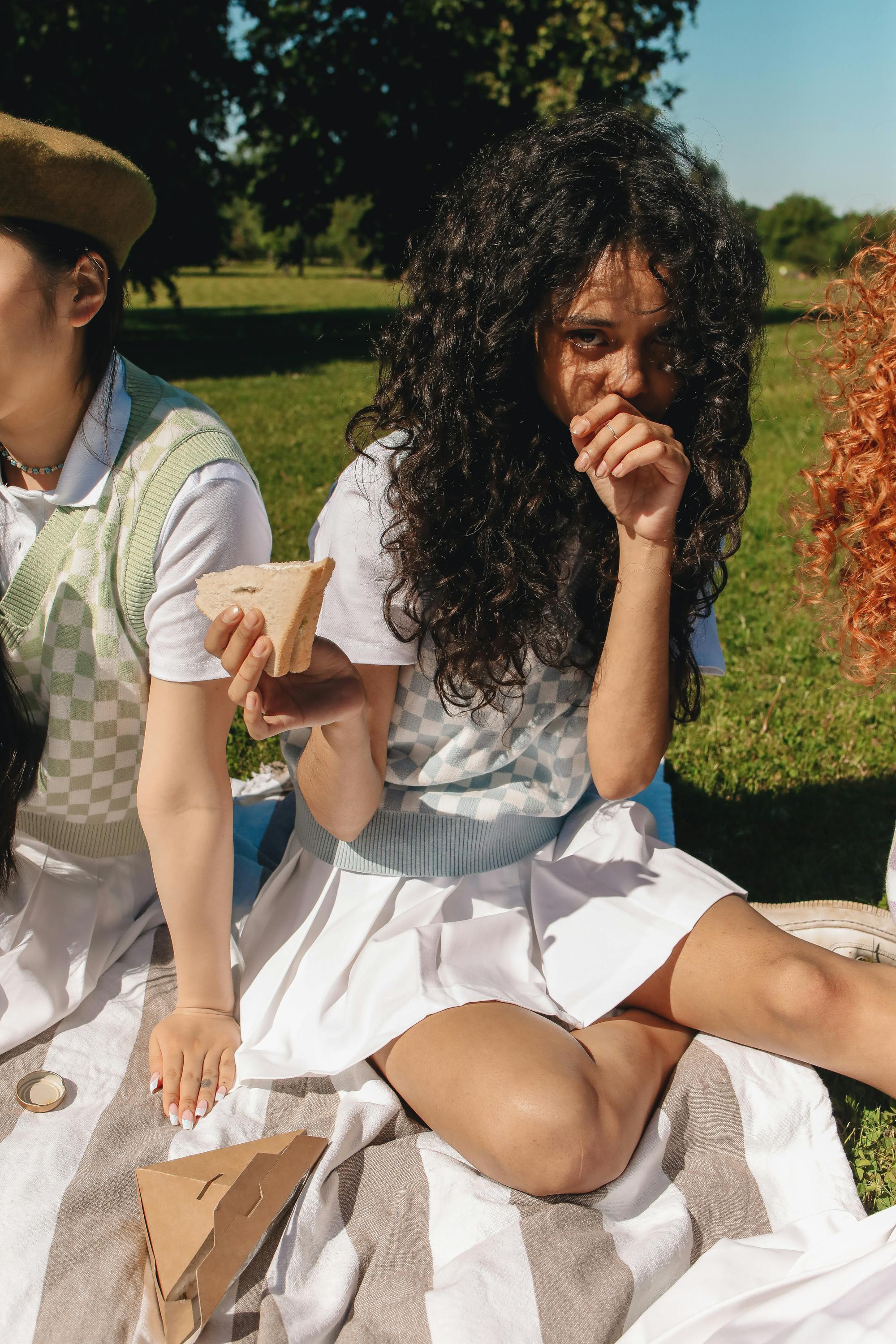 teenage girl holding a bread and sitting with her friends