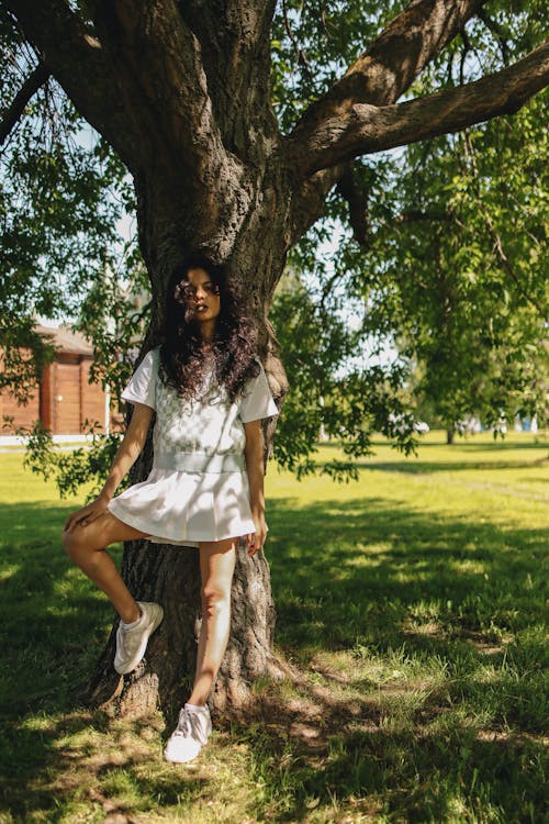 A Young Woman Posing by a Tree