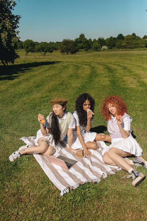 Free Women Sitting Together on a Picnic Blanket Stock Photo