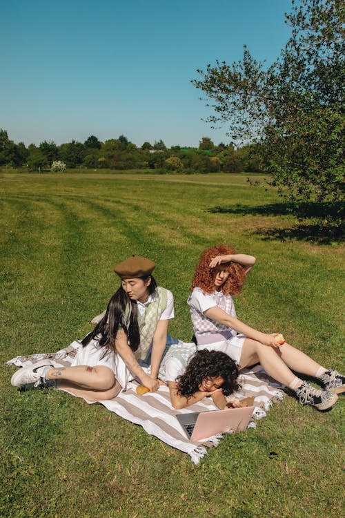 Young Women Sitting on a Picnic Blanket at a Park · Free Stock Photo
